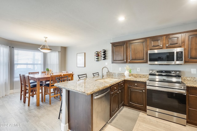 kitchen with kitchen peninsula, a kitchen breakfast bar, stainless steel appliances, and sink