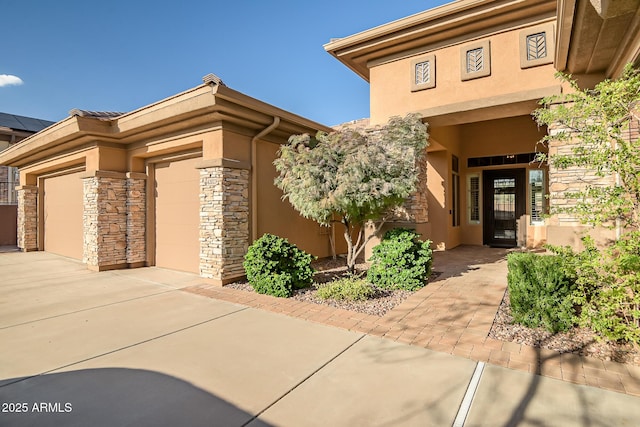 42023 N Bridlewood Way, Anthem, AZ 85086 - doorway to property with stucco siding, stone siding, an attached garage, and concrete driveway