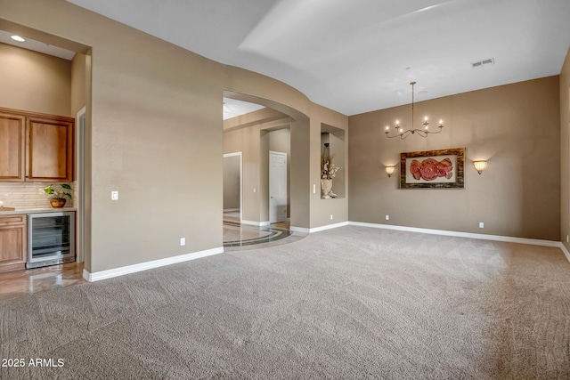 42023 N Bridlewood Way, Anthem, AZ 85086 - unfurnished room with beverage cooler, light colored carpet, arched walkways, baseboards, and bar