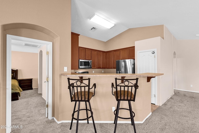 1623 E Maplewood Ave, Buckeye, AZ 85326 - kitchen featuring appliances with stainless steel finishes, light carpet, arched walkways, and lofted ceiling
