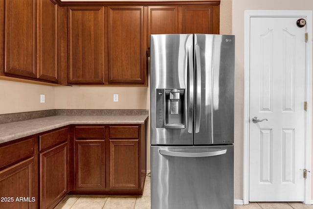 1623 E Maplewood Ave, Buckeye, AZ 85326 - kitchen featuring stainless steel fridge, light tile patterned floors, and brown cabinets
