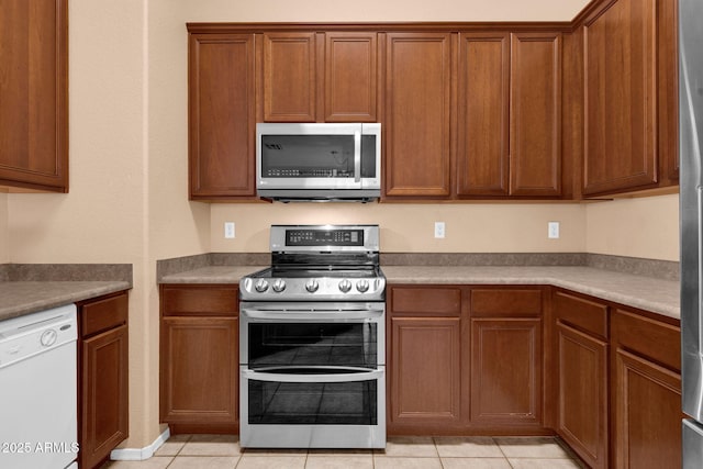 1623 E Maplewood Ave, Buckeye, AZ 85326 - kitchen featuring appliances with stainless steel finishes, light tile patterned floors, and brown cabinetry