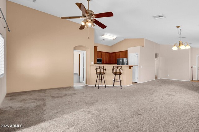 1623 E Maplewood Ave, Buckeye, AZ 85326 - unfurnished living room with arched walkways, a ceiling fan, light colored carpet, a chandelier, and high vaulted ceiling