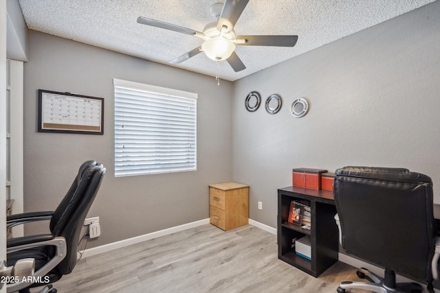 office space with a ceiling fan, light wood-style floors, a textured ceiling, and baseboards