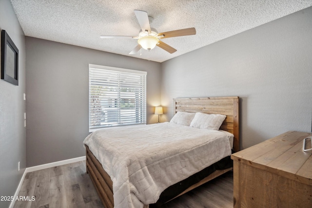 bedroom featuring a ceiling fan, a textured ceiling, wood finished floors, and baseboards