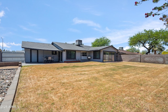 back of property featuring a yard, a fenced backyard, a patio, and central AC