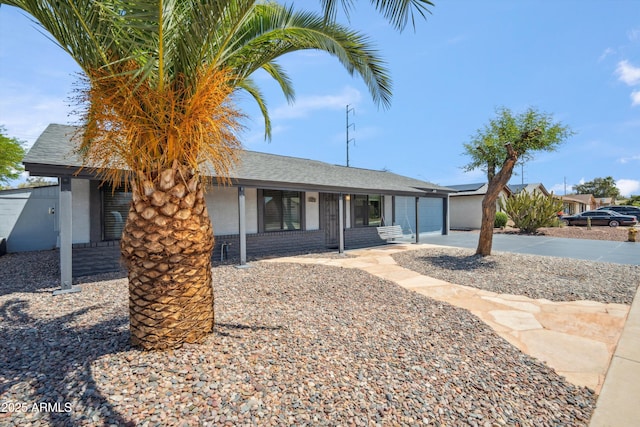 ranch-style house featuring an attached garage, concrete driveway, and a shingled roof