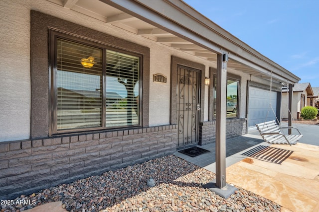 view of exterior entry with a porch and stucco siding