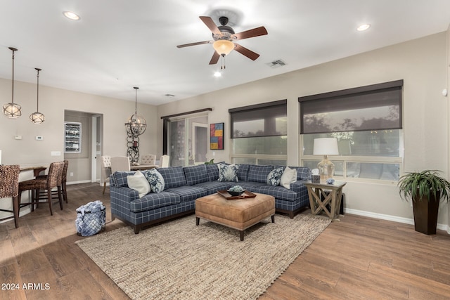 living room with hardwood / wood-style flooring, ceiling fan with notable chandelier, and plenty of natural light