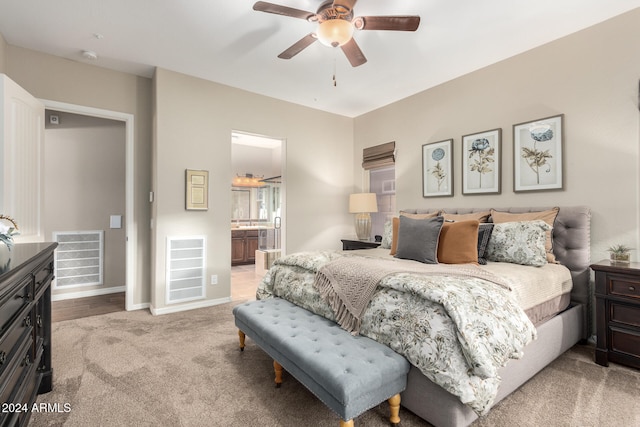 bedroom featuring ensuite bath, light colored carpet, and ceiling fan