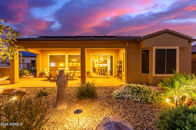 back house at dusk featuring a patio area