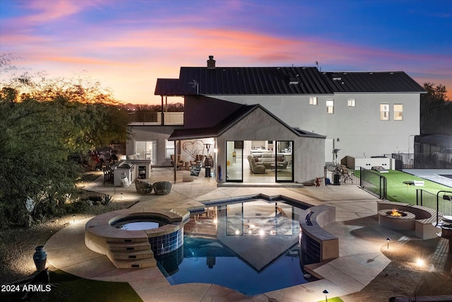 back house at dusk featuring a fire pit, a patio area, and a pool with hot tub