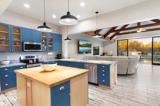 kitchen with a center island, blue cabinets, decorative light fixtures, and appliances with stainless steel finishes