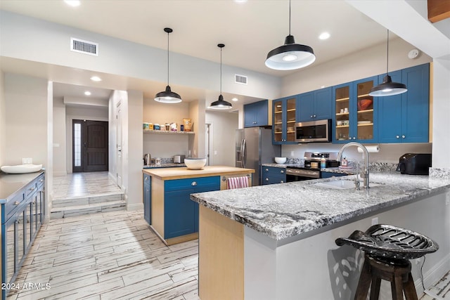 kitchen with blue cabinetry, sink, kitchen peninsula, and stainless steel appliances