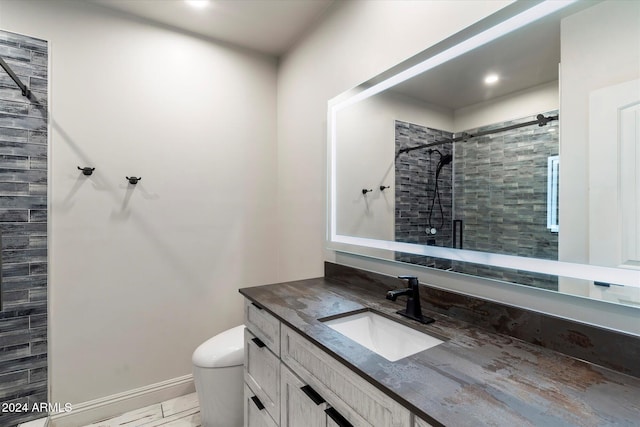 bathroom featuring a tile shower, vanity, and toilet