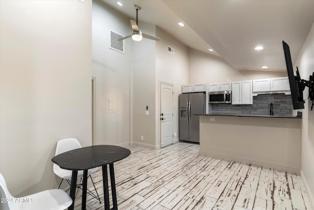 kitchen featuring backsplash, high vaulted ceiling, white cabinets, ceiling fan, and appliances with stainless steel finishes