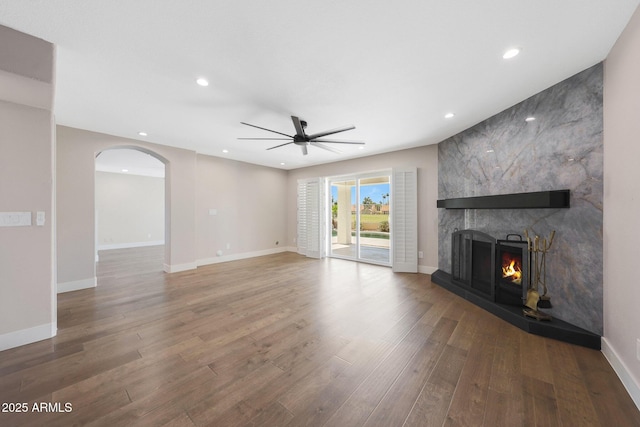 7535 W Kimberly Way, Glendale, AZ 85308 - unfurnished living room featuring a ceiling fan, a fireplace, wood finished floors, arched walkways, and recessed lighting