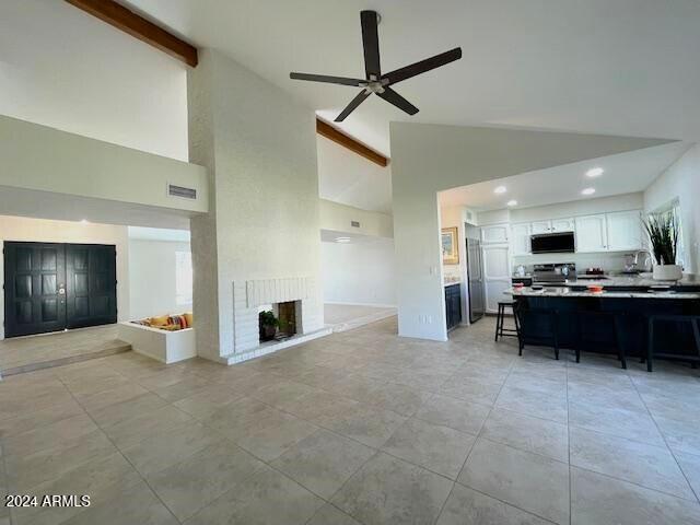 living room featuring ceiling fan, high vaulted ceiling, beamed ceiling, and a fireplace