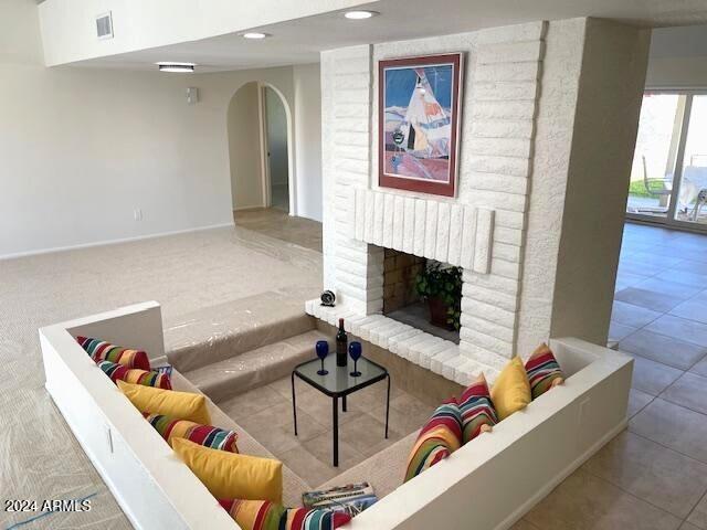 living room with light tile patterned flooring and a brick fireplace