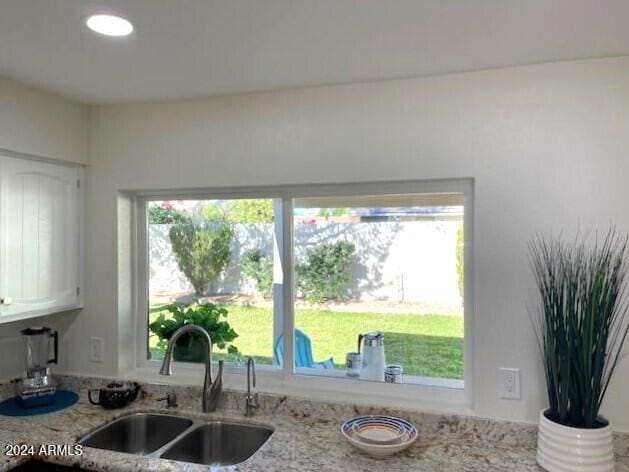 kitchen featuring white cabinetry, sink, and light stone counters