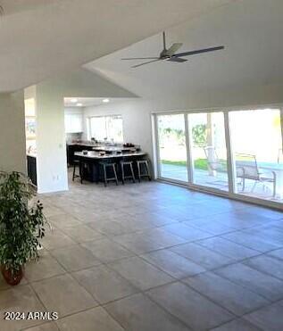 unfurnished living room with ceiling fan and high vaulted ceiling