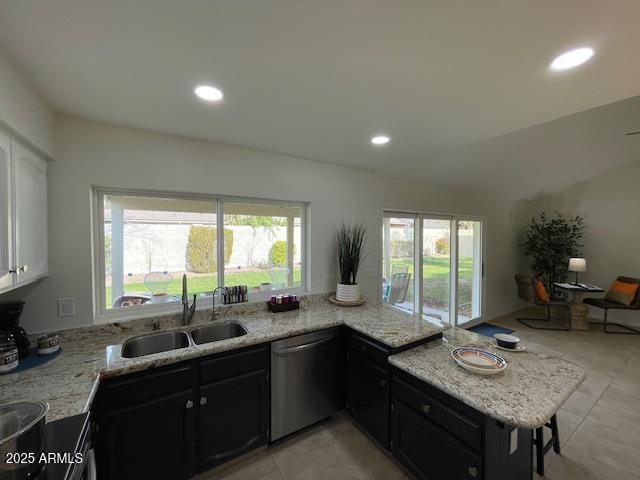 kitchen with sink, dishwasher, white cabinetry, light stone countertops, and light tile patterned flooring