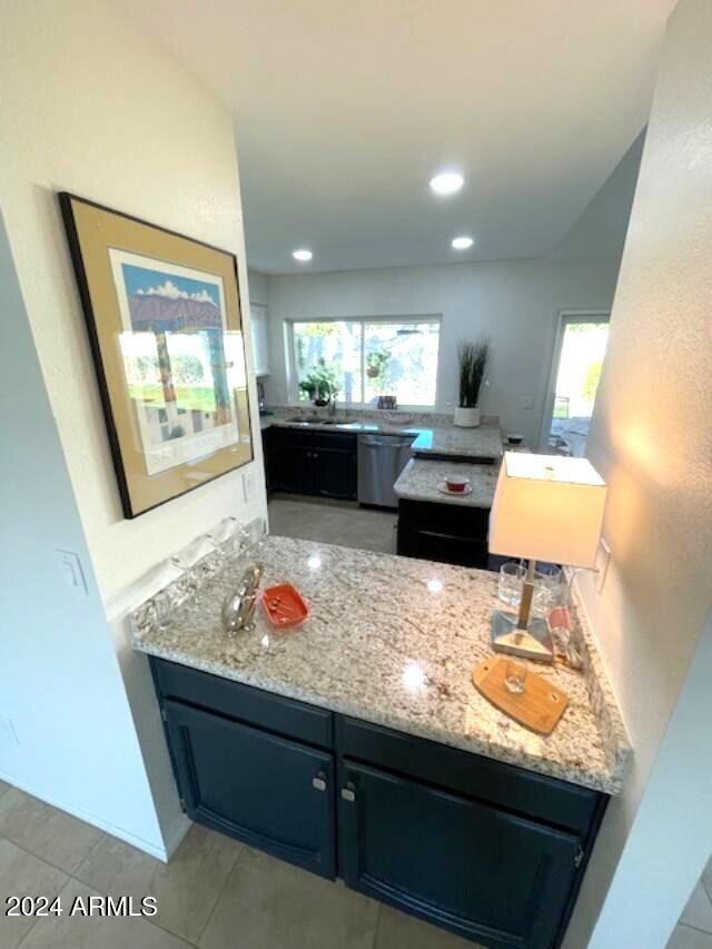 kitchen featuring light stone counters, sink, and stainless steel dishwasher