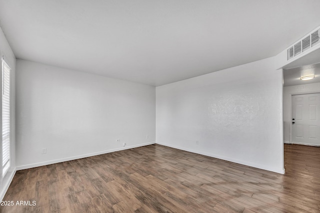 unfurnished room with visible vents, baseboards, and wood finished floors