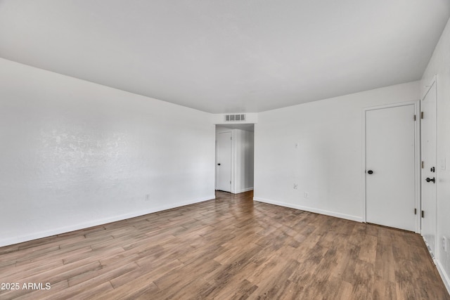 unfurnished room with visible vents, baseboards, and wood finished floors