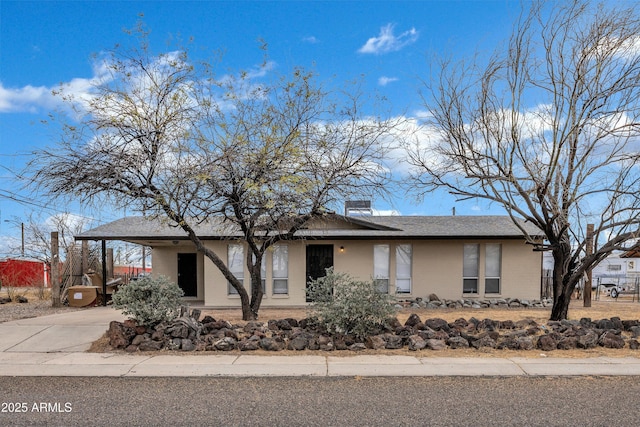 view of front of home featuring a carport, concrete driveway, and a chimney