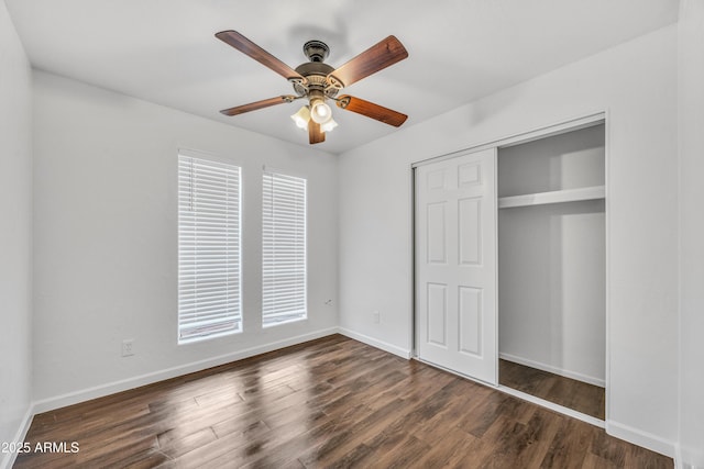 unfurnished bedroom featuring a closet, baseboards, wood finished floors, and a ceiling fan