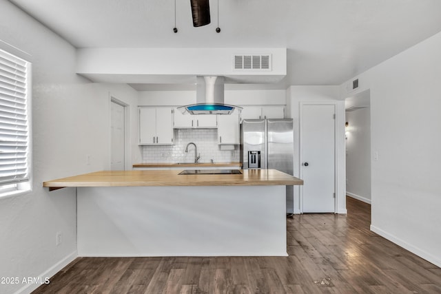 kitchen with visible vents, backsplash, stainless steel refrigerator with ice dispenser, island range hood, and white cabinetry