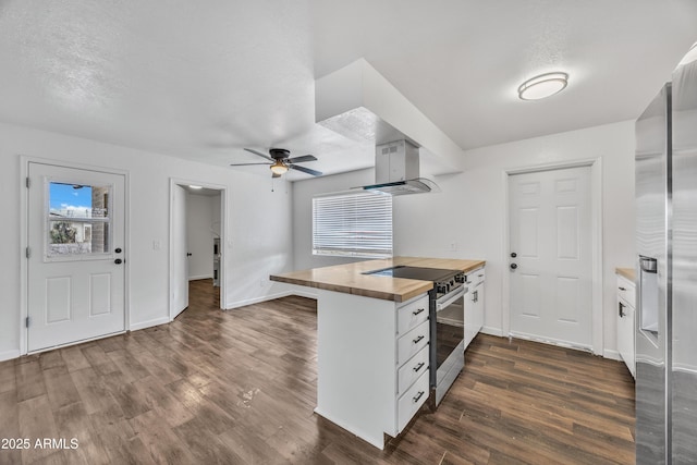 kitchen with wooden counters, ceiling fan, wall chimney range hood, dark wood finished floors, and stainless steel appliances