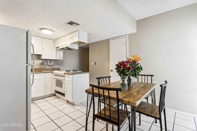 kitchen featuring light tile patterned floors, white appliances, and white cabinets