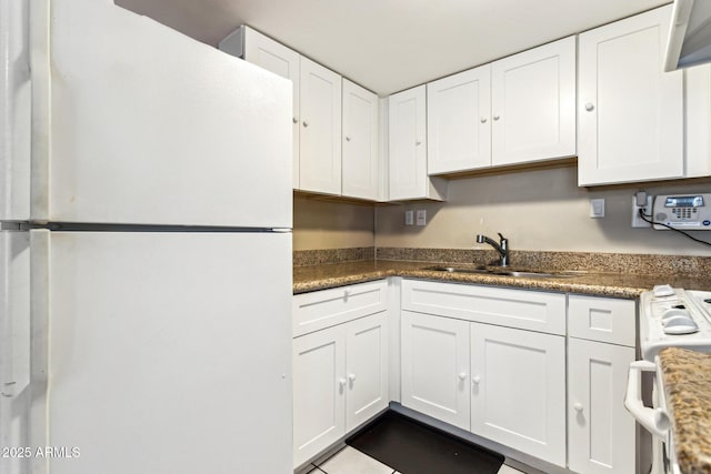 kitchen featuring sink, dark stone countertops, white cabinets, and white appliances