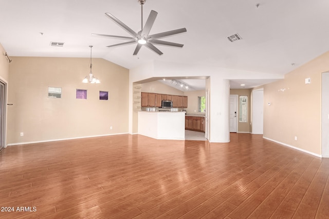 unfurnished living room featuring hardwood / wood-style flooring, ceiling fan with notable chandelier, and vaulted ceiling