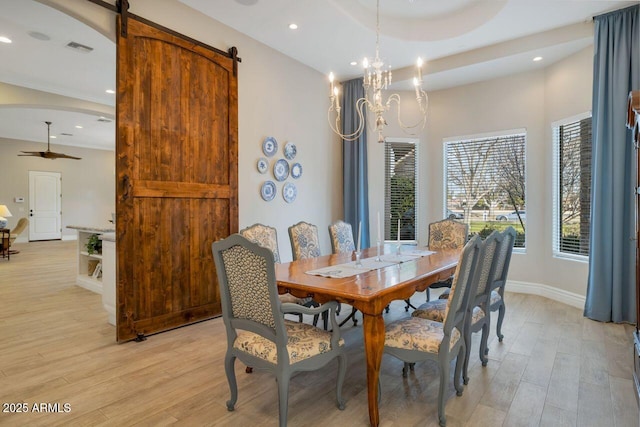 dining space with ceiling fan with notable chandelier, light hardwood / wood-style floors, and a barn door