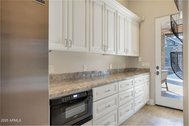 kitchen featuring white cabinetry, wall oven, light stone countertops, and luxury fridge