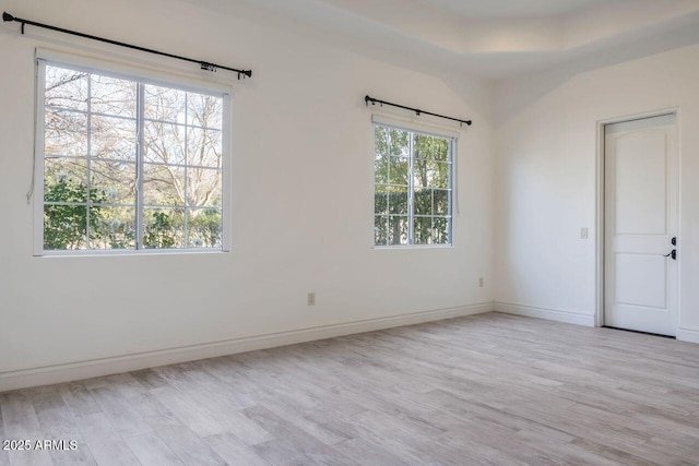 unfurnished bedroom featuring a raised ceiling and light hardwood / wood-style flooring