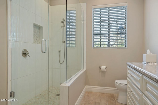 bathroom with toilet, plenty of natural light, vanity, and walk in shower