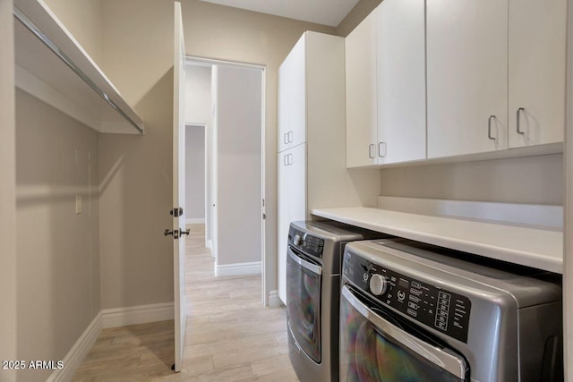 laundry room featuring cabinets, washer and clothes dryer, and light hardwood / wood-style flooring