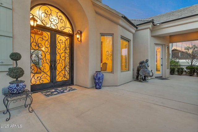 view of exterior entry with a patio area and french doors