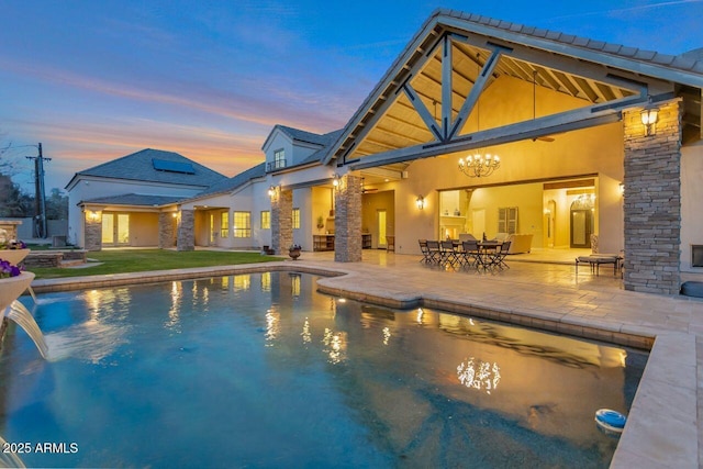 pool at dusk with a patio area