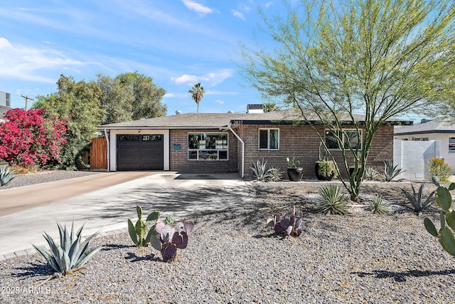 single story home with an attached garage, brick siding, driveway, and fence
