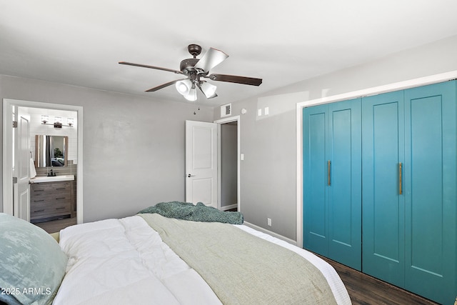 bedroom with dark wood finished floors, a closet, ceiling fan, ensuite bathroom, and baseboards