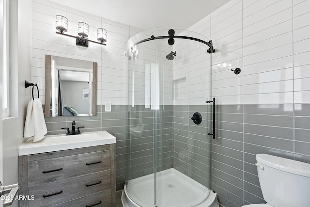 bathroom featuring tile walls, a stall shower, vanity, toilet, and tasteful backsplash