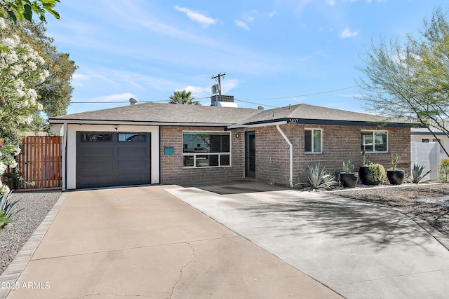 ranch-style house with a garage, concrete driveway, brick siding, roof with shingles, and fence