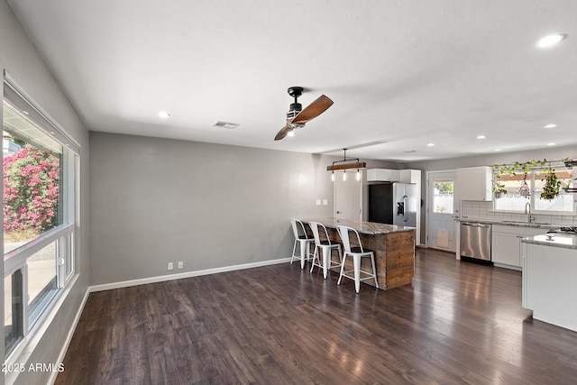 kitchen featuring appliances with stainless steel finishes, a breakfast bar area, a sink, dark wood-type flooring, and white cabinets