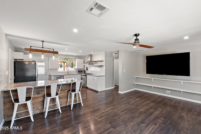 kitchen featuring stainless steel appliances, recessed lighting, a breakfast bar, dark wood finished floors, and tasteful backsplash