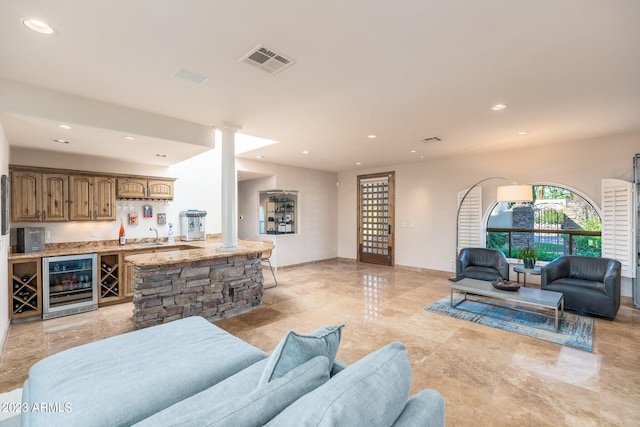 living room featuring bar, wine cooler, and decorative columns